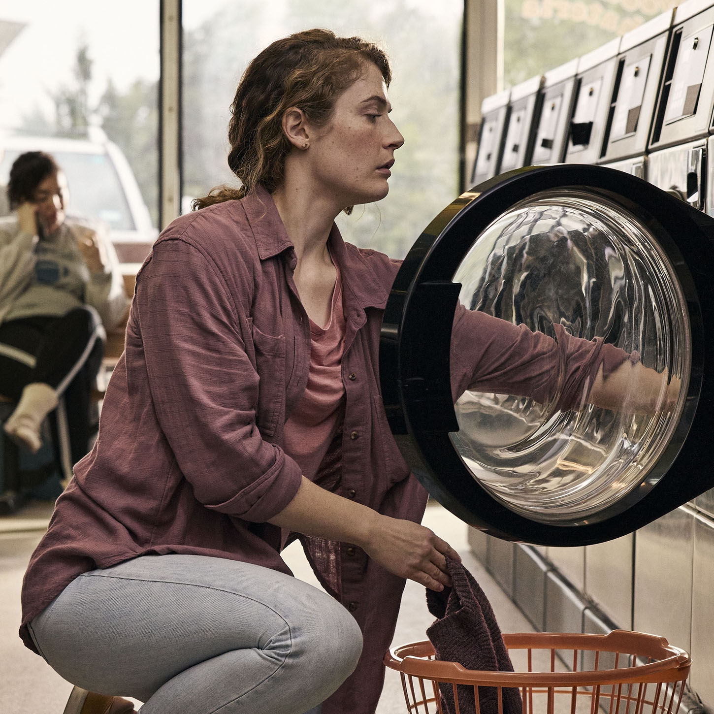 woman taking laundry out of machine at laundromat